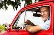 Mature man enjoying a road trip in a small red car