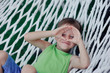 Boy in green shirt playing in a big hammock on the nature of the