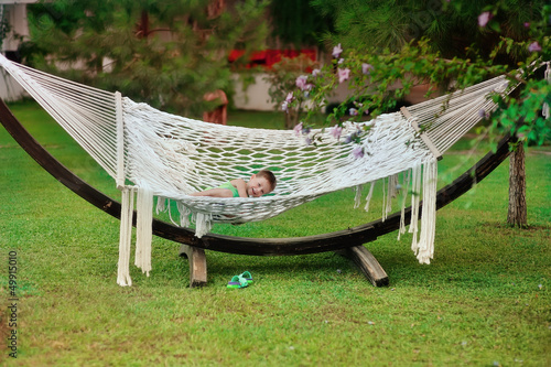 Photo: Boy in green shirt swinging in a hammock on a large nature park Boy in green shirt swinging in a hammock on a large nature park