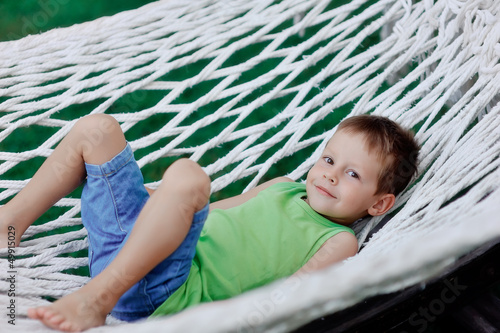 Photo: Boy in green shirt swinging in a hammock on a large nature park Boy in green shirt swinging in a hammock on a large nature park
