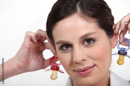 Photo: Woman holding baby soothers near her ears Woman holding baby soothers near her ears