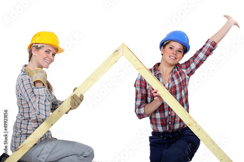 Photo: Peppy tradeswomen holding up a wooden frame Peppy tradeswomen holding up a wooden frame