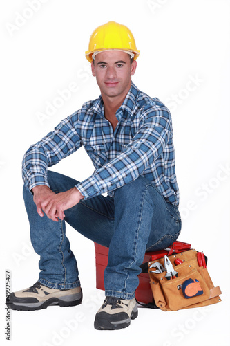 Photo: A construction worker sitting on his toolbox. A construction worker sitting on his toolbox.