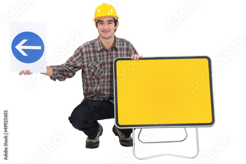 Photo: Man kneeling by two traffic signs Man kneeling by two traffic signs