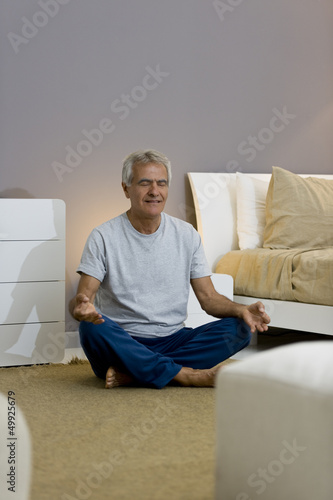 Photo: Mature man doing yoga in bedroom Mature man doing yoga in bedroom