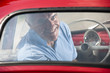 Mature man enjoying a road trip in a small red car