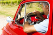 Mature man enjoying a road trip in a small red car