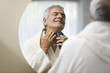 Mature man shaving in bathroom mirror
