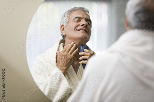 Photo: Mature man shaving in bathroom mirror Mature man shaving in bathroom mirror