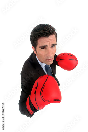 Photo: A businessman with boxing gloves on. A businessman with boxing gloves on.