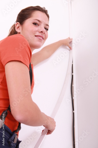 Photo: Smiling woman hiding cable on wall Smiling woman hiding cable on wall