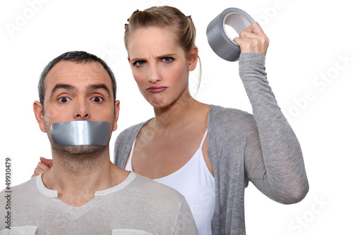 Photo: Woman taping boyfriends mouth closed Woman taping boyfriends mouth closed