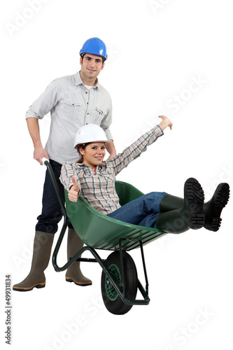 Photo: Construction couple playing with a wheelbarrow Construction couple playing with a wheelbarrow
