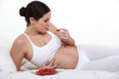 Pregnant brunette eating strawberries