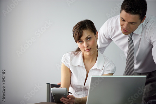 Photo: employee at her desk with colleague employee at her desk with colleague