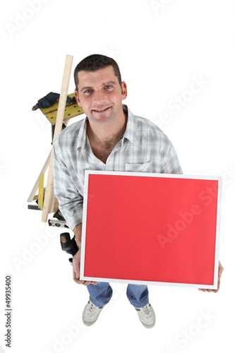 Photo: Handyman with a board left blank for your message Handyman with a board left blank for your message