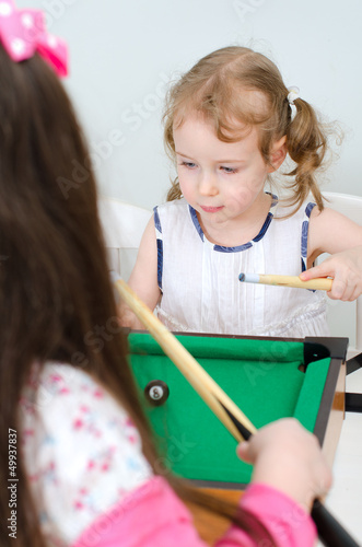 Photo: Two little girls playing mini billiard Two little girls playing mini billiard