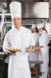 Chef Presenting Dish In Commercial Kitchen