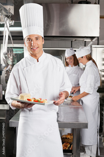 Photo: Chef Presenting Dish In Commercial Kitchen Chef Presenting Dish In Commercial Kitchen