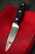 Blutiges Küchenmesser auf einer roten Stoffserviette