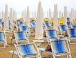 Photo: sun beds and umbrellas closed in a deserted sandy beach sun beds and umbrellas closed in a deserted sandy beach