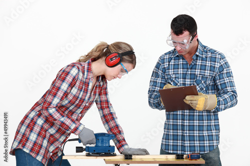 Photo: Man evaluating a tradeswoman on her use of a jigsaw Man evaluating a tradeswoman on her use of a jigsaw