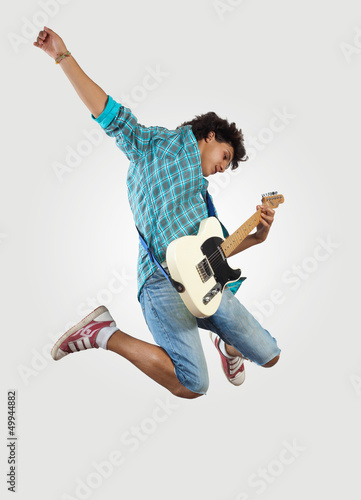 Photo: young man playing on electro guitar and jumping young man playing on electro guitar and jumping