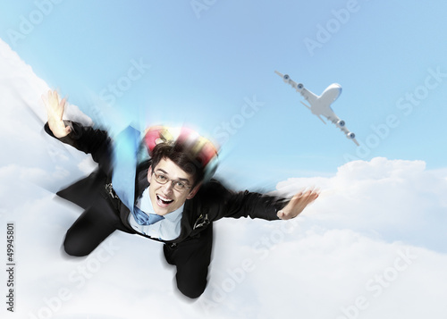 Photo: Young businessman flying with parachute on back Young businessman flying with parachute on back