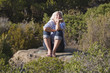 smiling grey hair woman enjoying to relax on a rock 