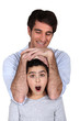 Man laying his arms over a surprised girl's head