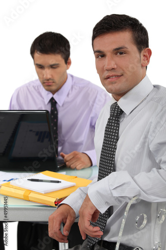 Photo: Two business colleagues sat at desk Two business colleagues sat at desk