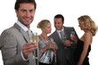 Man making a toast with champagne as his friends chat