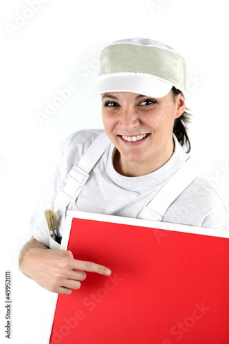 Photo: Happy female decorator pointing at red panel Happy female decorator pointing at red panel