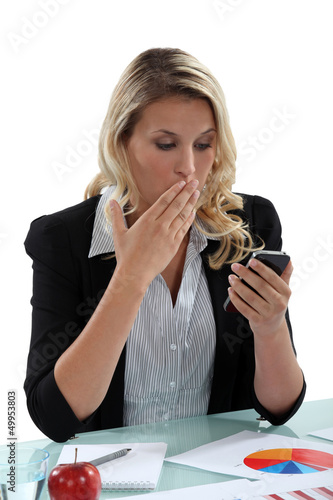 Photo: Businesswoman in shock at a phone message Businesswoman in shock at a phone message