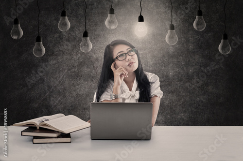 Photo: Beautiful student looking at lit bulb Beautiful student looking at lit bulb