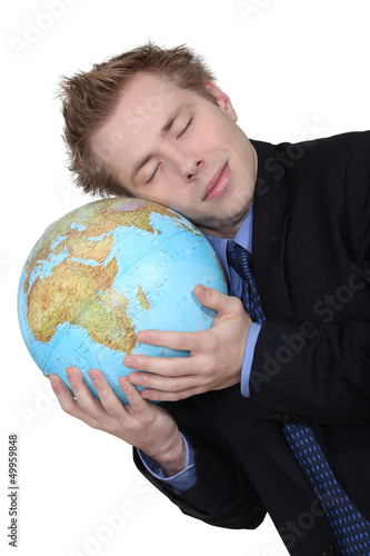 Photo: A businessman loving his globe. A businessman loving his globe.