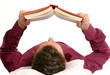 Hombre joven recostado leyendo un libro.