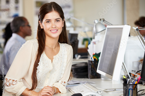 Photo: Woman Working At Desk In Busy Creative Office Woman Working At Desk In Busy Creative Office