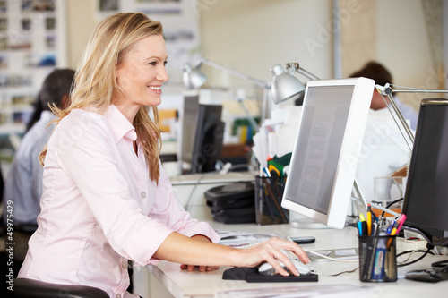 Photo: Woman Working At Desk In Busy Creative Office Woman Working At Desk In Busy Creative Office