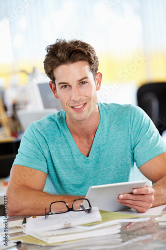 Photo: Man Using Digital Tablet In Busy Creative Office Man Using Digital Tablet In Busy Creative Office