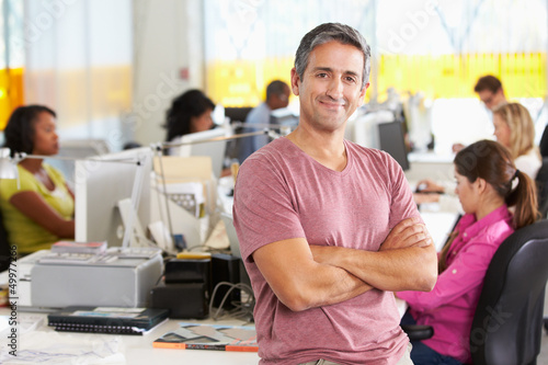 Photo: Portrait Of Man Standing In Busy Creative Office Portrait Of Man Standing In Busy Creative Office
