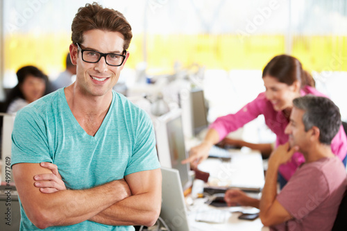 Photo: Portrait Of Man Standing In Busy Creative Office Portrait Of Man Standing In Busy Creative Office