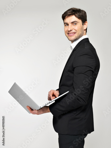 Photo: Portrait of young man with laptop in casuals Portrait of young man with laptop in casuals