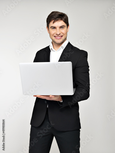 Photo: Portrait of young man with laptop in casuals Portrait of young man with laptop in casuals