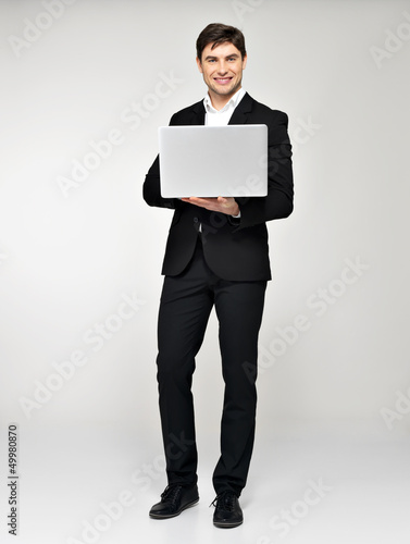 Photo: Full portrait of young man with laptop in casuals Full portrait of young man with laptop in casuals