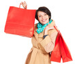 Happy woman with shopping bags in beige autumn coat