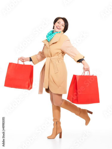 Photo: Portrait of happy woman with shopping bags in autumn coat Portrait of happy woman with shopping bags in autumn coat