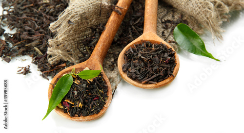 Photo: Dry tea with green leaves in wooden spoons, isolated on white Dry tea with green leaves in wooden spoons, isolated on white