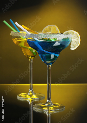 Photo: Yellow and blue cocktails in glasses on color background Yellow and blue cocktails in glasses on color background