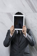 Photo: Businessman holding a digital tablet up over his face. Businessman holding a digital tablet up over his face.